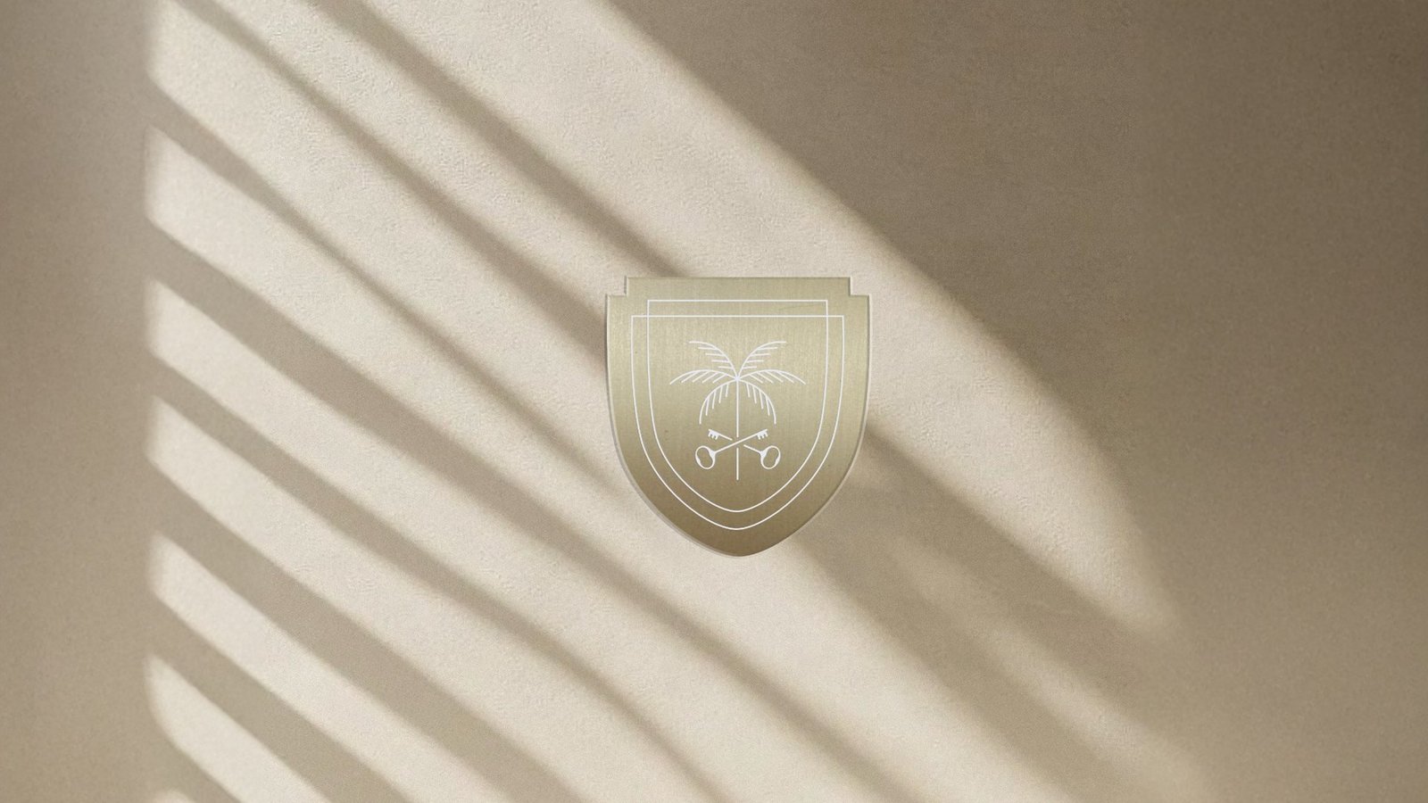 Residences crest in gold foil, shadow across cream linen